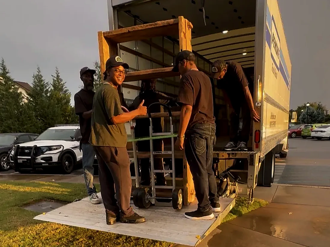 Carter's Care crew loading furniture with a hand truck up a ramp